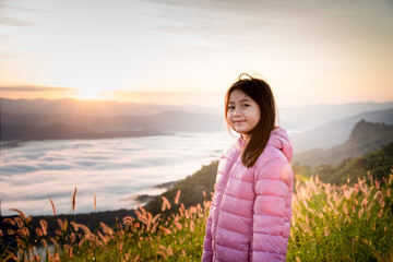 A Cute girl who is a tourist Wear a pink sweater Come up to see the beautiful mountain and sea mist. While looking at the sunrise