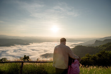 Father and daughter stand and watch the beautiful mountain view and Sea of mist with sun rising.