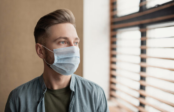 Sad Man Alone During Coronavirus Pandemic Wearing Face Mask Indoors At Home For Social Distancing. Anxiety, Stress, Lockdown, Mental Health Crisis, Coronavirus Concept