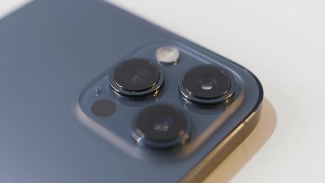 Close up details of a beautiful dark blue smartphone with three cameras. Action. Concept of modern technologies and design, device isolated on white background.