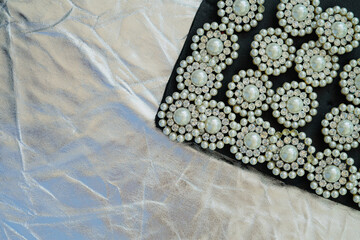 round brooch with pearls on a black and silver background.