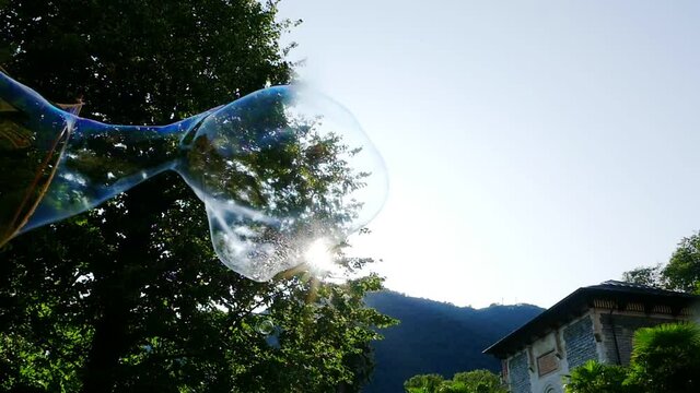 Big soap bubble being made and floating in the air then explode in slow motion