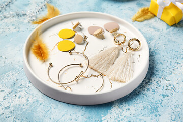 Plate with beautiful jewelry on color background