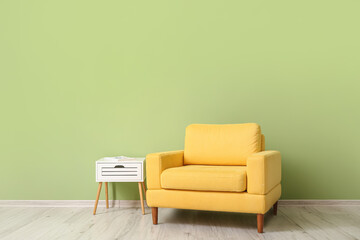Armchair with table near color wall in room