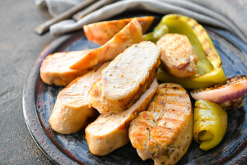 Board with cooked chicken fillet on dark background