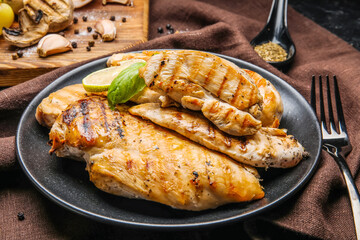 Plate with cooked chicken fillet on dark background