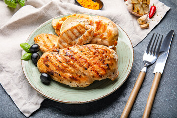 Plate with cooked chicken fillet on dark background