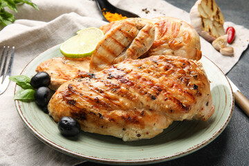 Plate with cooked chicken fillet on dark background