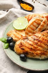 Plate with cooked chicken fillet on dark background