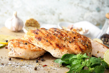 Board with cooked chicken fillet on table