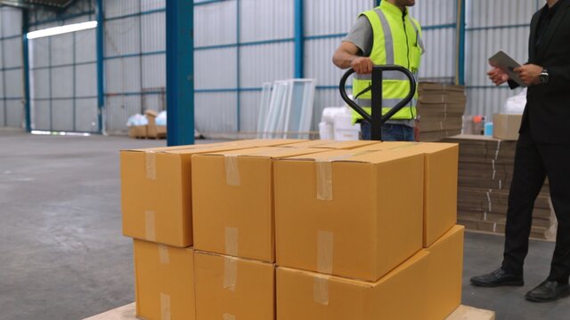 Factory workers deliver boxes package on a pushing trolley in the warehouse . Industry supply chain management concept .
