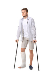 Young man with broken leg on white background