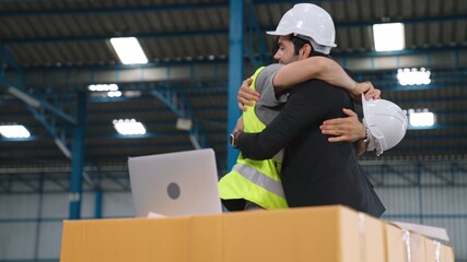Two factory worker celebrate success together in the factory or warehouse . Industry work achievement concept .