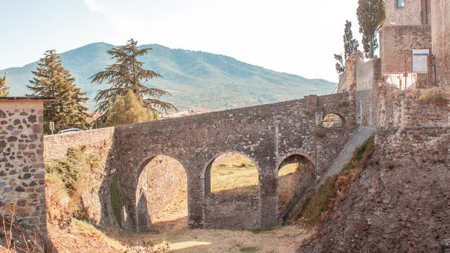 Time lapse of Melfi's castle, a medieval stone bricks castle with towers in south of Ttaly during a sunny cloudy day. There is a stone bridge and tower and countryside around it