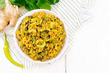Kitchari with celery in bowl on light board top