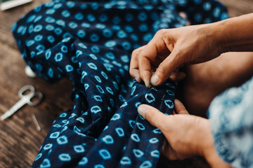 Asian woman's hand is embroidered with tribal native fabric (dyed indigo color). folk art, crafts.
