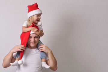 Fototapeta na wymiar a little girl with a Santa hat on her dad's shoulders
