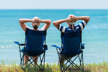 man and woman relax and unwind in camping chairs on the seashore