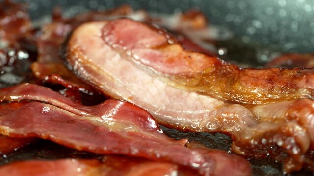 Super Slow Motion Shot of Roasted Bacon Slices Falling into Pan at 1000 fps.