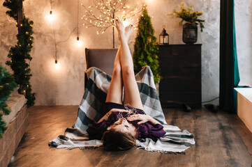 beautiful young girl for christmas in a happy mood against the background of a christmas tree and lights indoors
