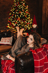 beautiful young girl for christmas in a happy mood against the background of a christmas tree and lights indoors