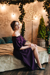 beautiful young girl for christmas in a happy mood against the background of a christmas tree and lights indoors
