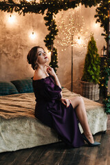 beautiful young girl for christmas in a happy mood against the background of a christmas tree and lights indoors