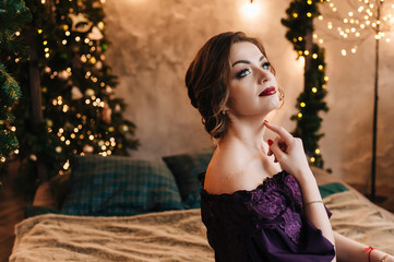 beautiful young girl for christmas in a happy mood against the background of a christmas tree and lights indoors
