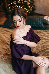 beautiful young girl for christmas in a happy mood against the background of a christmas tree and lights indoors