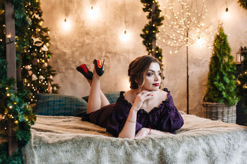 beautiful young girl for christmas in a happy mood against the background of a christmas tree and lights indoors