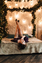 beautiful young girl for christmas in a happy mood against the background of a christmas tree and lights indoors