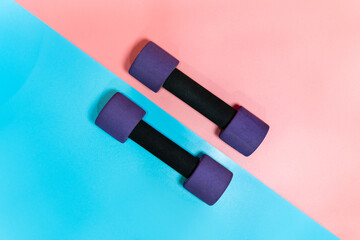 Top view of female dumbbells placed on pink and blue background