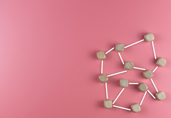 The concept of building relationships. Wooden cubes connected by lines. Pink background