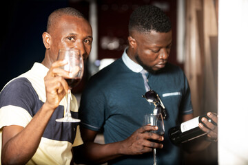 two handsome young people holding a glass of red wine