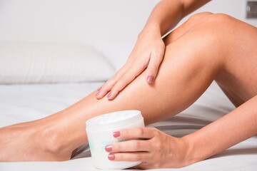 woman putting hand cream on her legs to keep them hydrated and healthy. Wellness, health and lifestyle concept