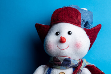 happy snowman with winter hat on blue background with copy space