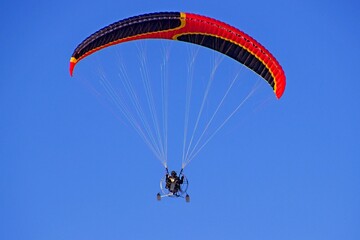 Paragliding against a bright blue sky. Hobby. Sport.