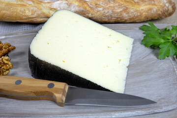 tranche de fromage tomme noire des Pyrenees sur une planche à découper