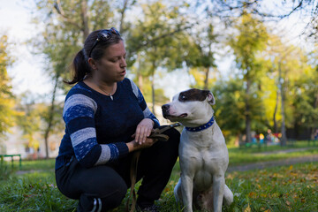 Young woman enjoys companionship with her beloved pet, a pit bull, in a city park. Selective focus