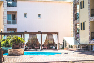 Luxury hotel with swimming pool in summer, hotel courtyard. Sun beds, greenery and windows. Summer...