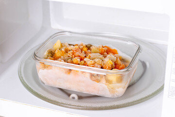 Frozen food in containers in the microwave, close up
