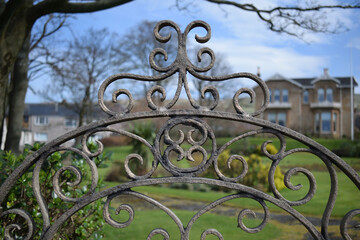 Fototapeta na wymiar Close Up of Ornate Iron Work on Gated Entrance of Large Victorian House 