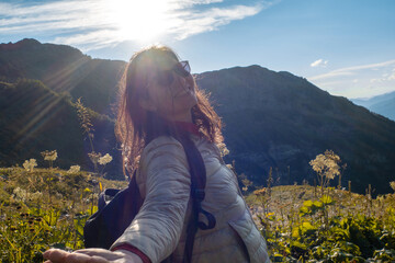 Naklejka premium Happy young woman on nature in the mountains, sun rays and glare.
