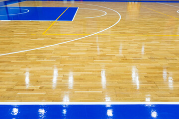 Top view of a part of an empty basketball court. the floor of the sports space is made of wood and painted blue