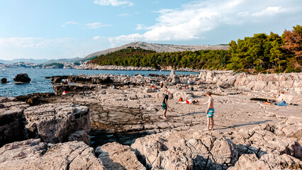 People enjoying a sunny day on Lokrum Island. People playing and sunbathing at a rocky beach on Lokrum island near Dubrovnik