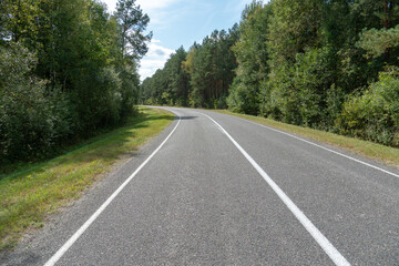 Fototapeta na wymiar Empty asphalt road through woods and fields. New fresh asphalt pavement away from the city. Development of rural infrastructure. Road marking lines close up.