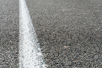 Empty asphalt road. New fresh asphalt pavement away from the city. Development of rural infrastructure. Road marking lines close up.