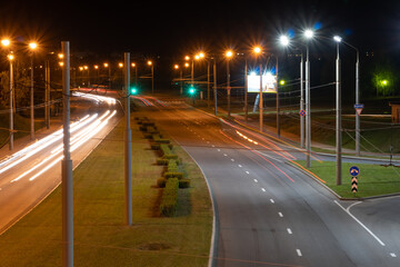 Night city light lines from cars. cars in highway with blur motion. Street view of the modern city at night. A lot of light from car headlights, advertising banners and night lights.