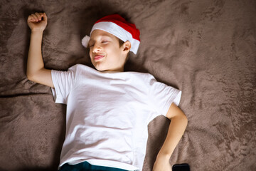 a child in a Christmas Santa hat is lying on a brown blanket