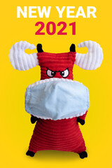 Red bull symbol of the new year 2021 in a medical mask. yellow background and inscription new year 2021